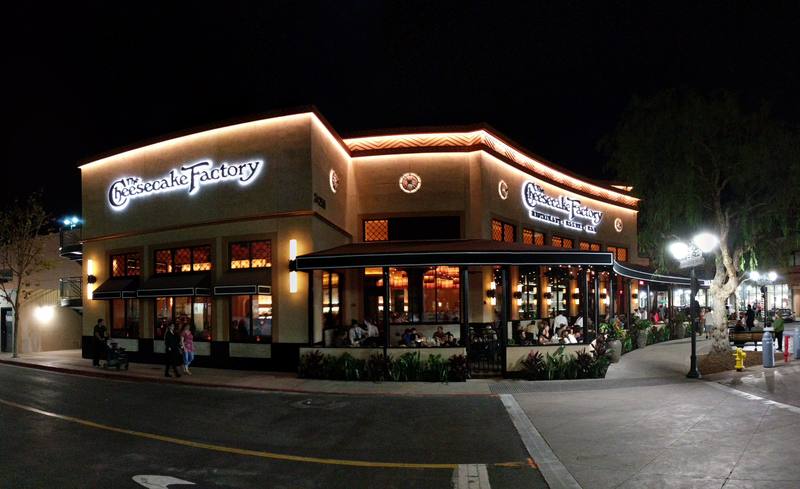 Corner view at night of a Cheesecake Factory restaurant with illuminated signage