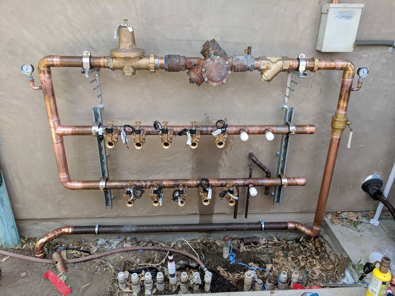 Copper manifold with backflow preventer and valves mounted on a wall