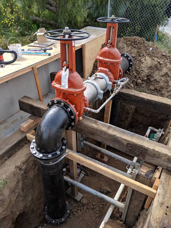 Ductile iron water service with red OS&Y gate valves in an excavation