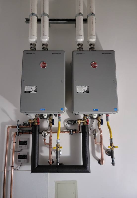 Two wall-mounted tankless water heaters with copper and gas piping