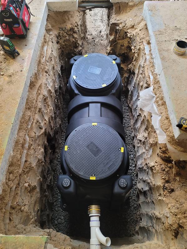 Black grease interceptor set in an excavated trench